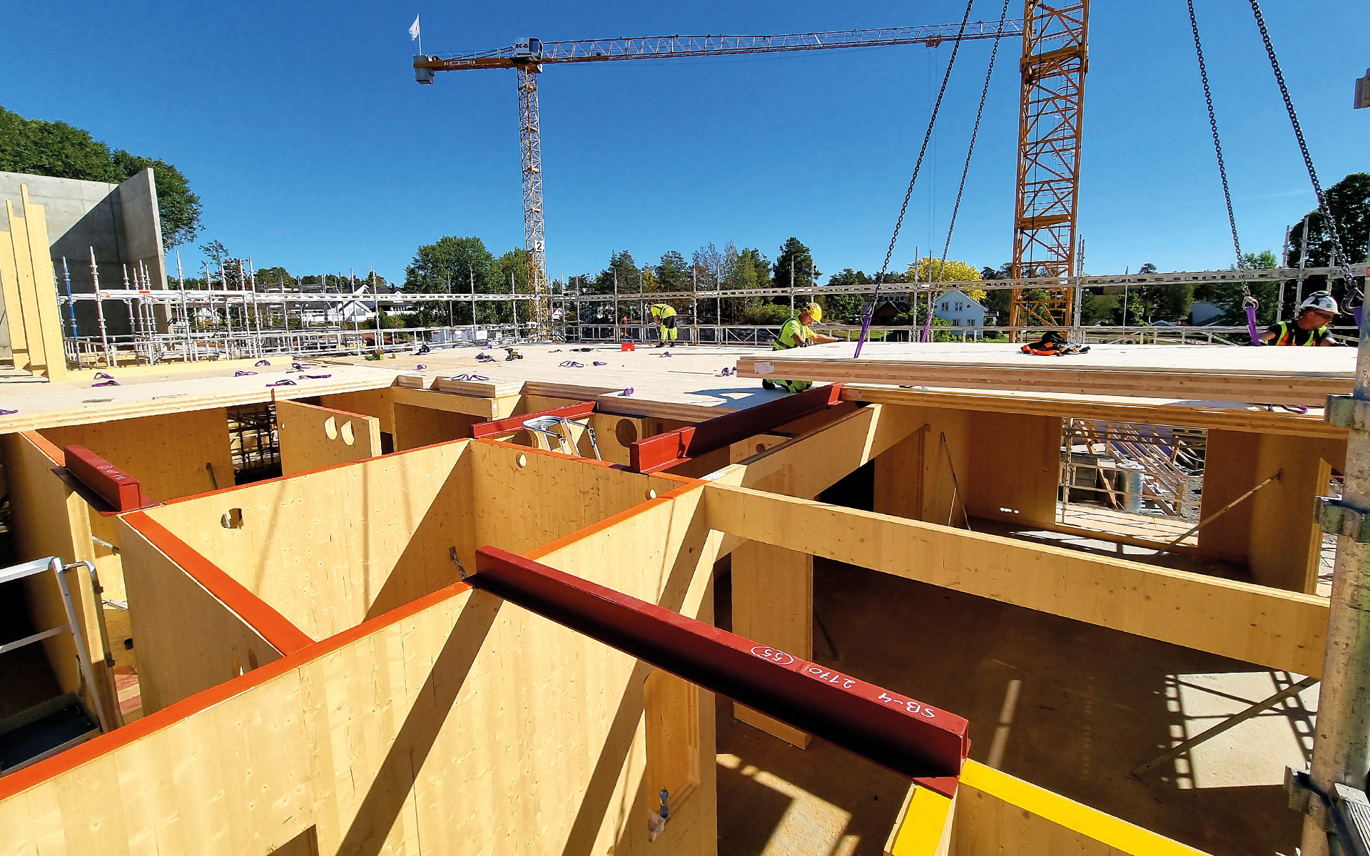 Mass timber construction site with CLT panels installation and workers assembling timber floor structure